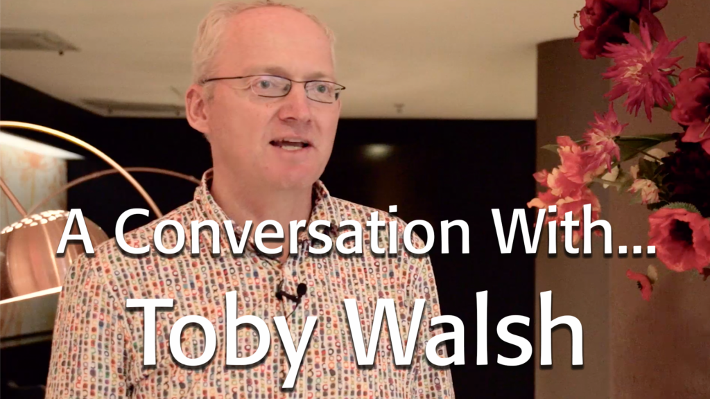 Image of Toby Walsh wearing a patterned shirt, in a hotel lobby.