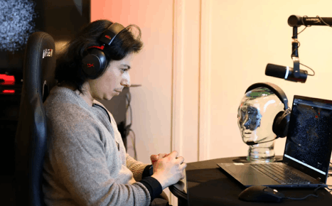 Ramses Alcaide wearing over-ear headphones while concentrating on a laptop computer screen.