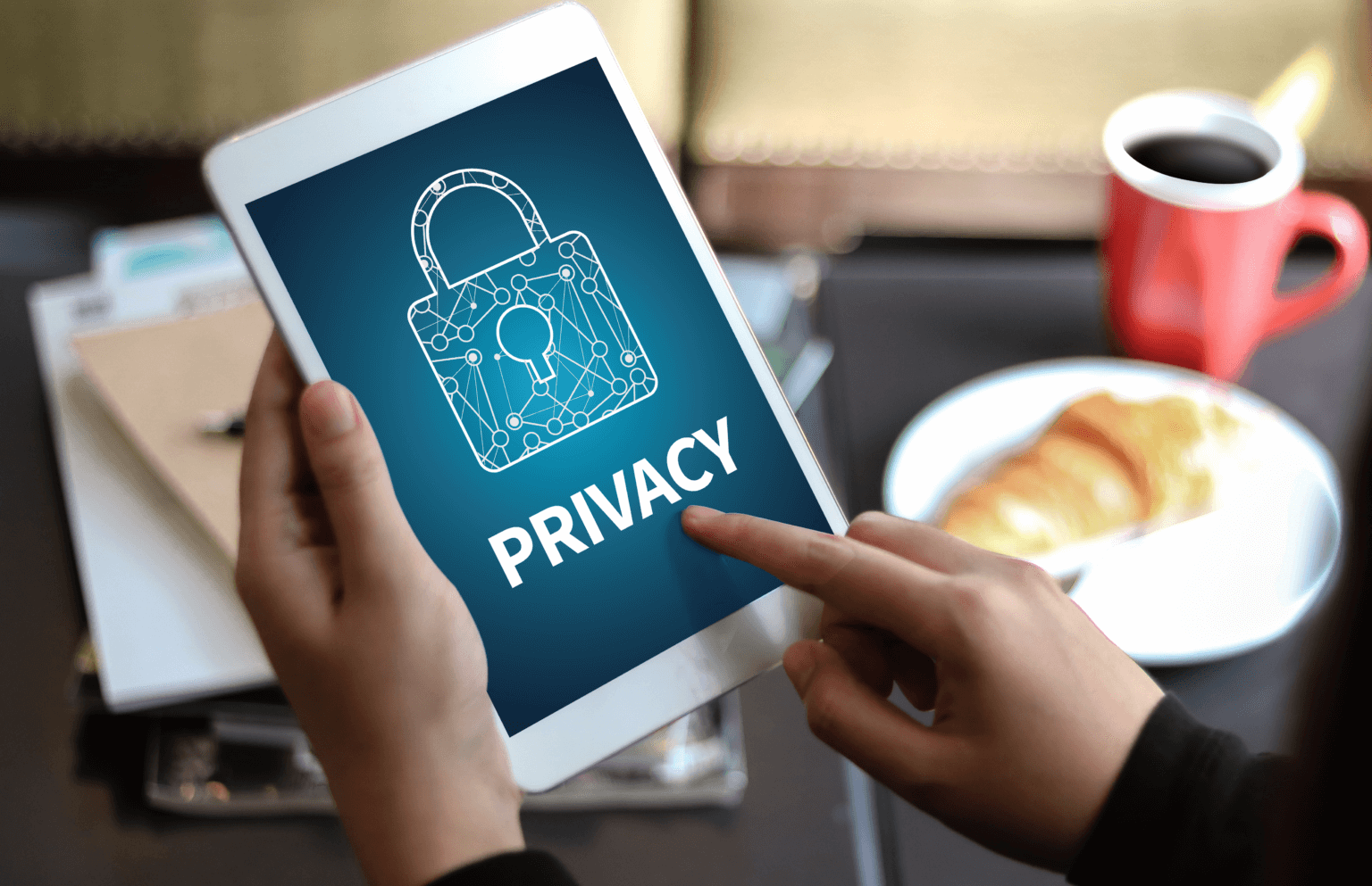 Hands are holding a tablet with an image of a padlock and the word Privacy on the screen